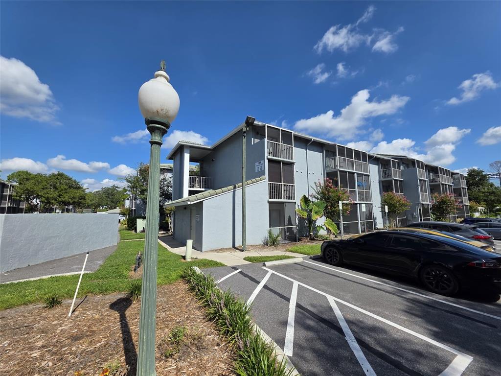 A multi-story apartment building with screened balconies stands next to a parking lot — 139 OYSTER BAY CIRCLE UNIT 220, ALTAMONTE SPRINGS, FL