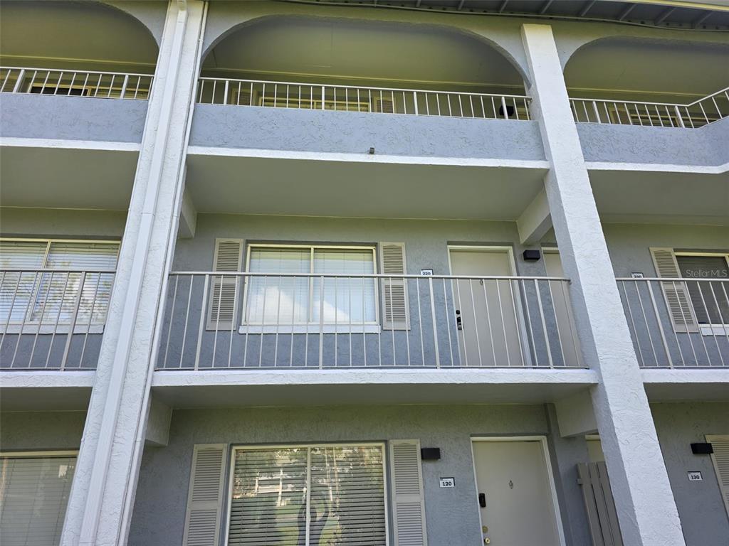 The exterior of a multi-story apartment building features balconies, sliding glass doors, and unit numbers — 139 OYSTER BAY CIRCLE UNIT 220, ALTAMONTE SPRINGS, FL