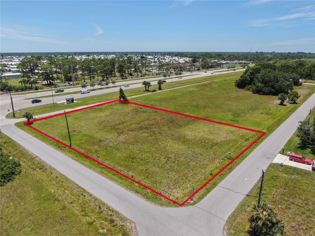 An aerial view shows a vacant, rectangular plot of land outlined in red near a road — 11996 TAMIAMI TRAIL S, NORTH PORT, FL