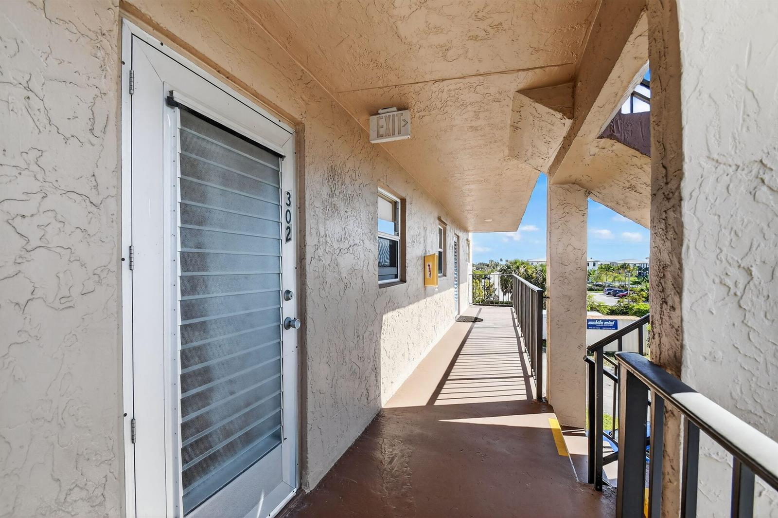 An exterior walkway leads to a numbered apartment door with a screen door — 729 Lori Drive # 302, Palm Springs FL 33461, PALM SPRINGS, FL
