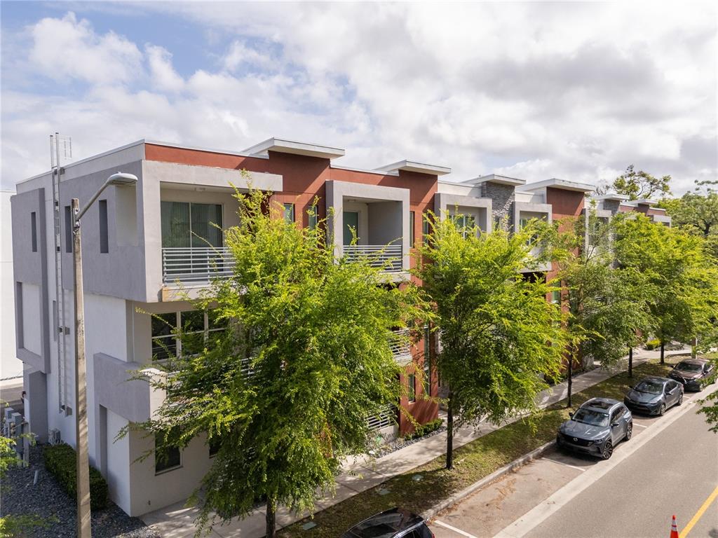 A multi-story residential building with balconies and trees sits along a street with parked cars — 73 W GRANT STREET, ORLANDO, FL