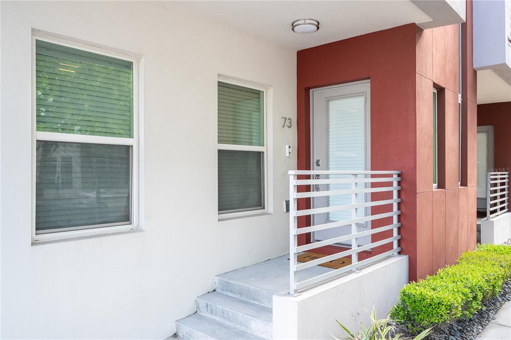 A white exterior wall with two windows, a red accent wall, and a front entrance — 73 W GRANT STREET, ORLANDO, FL