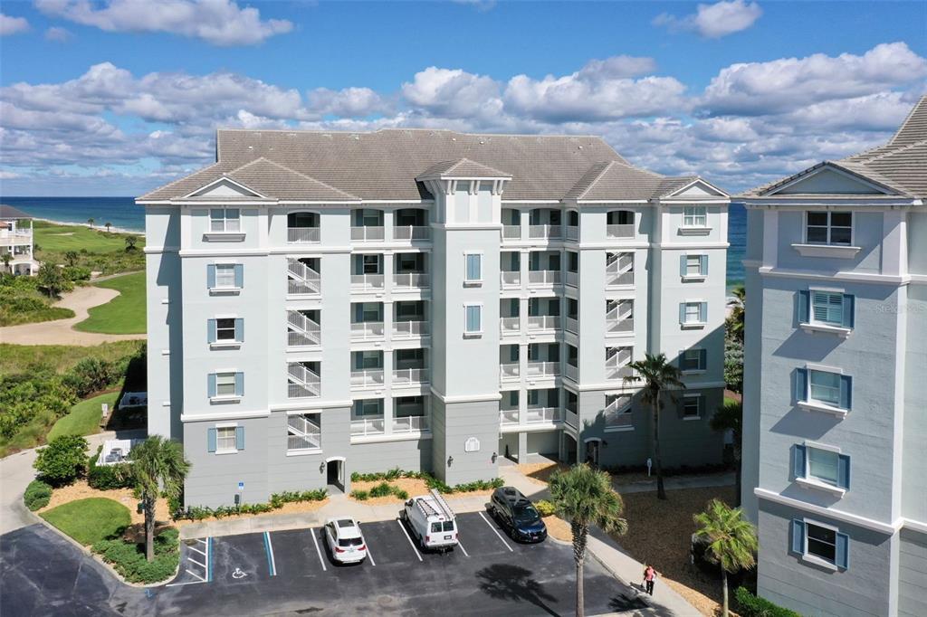 An aerial view of a multi-story coastal apartment building with a parking lot below — 500 CINNAMON BEACH WAY UNIT 452, PALM COAST, FL