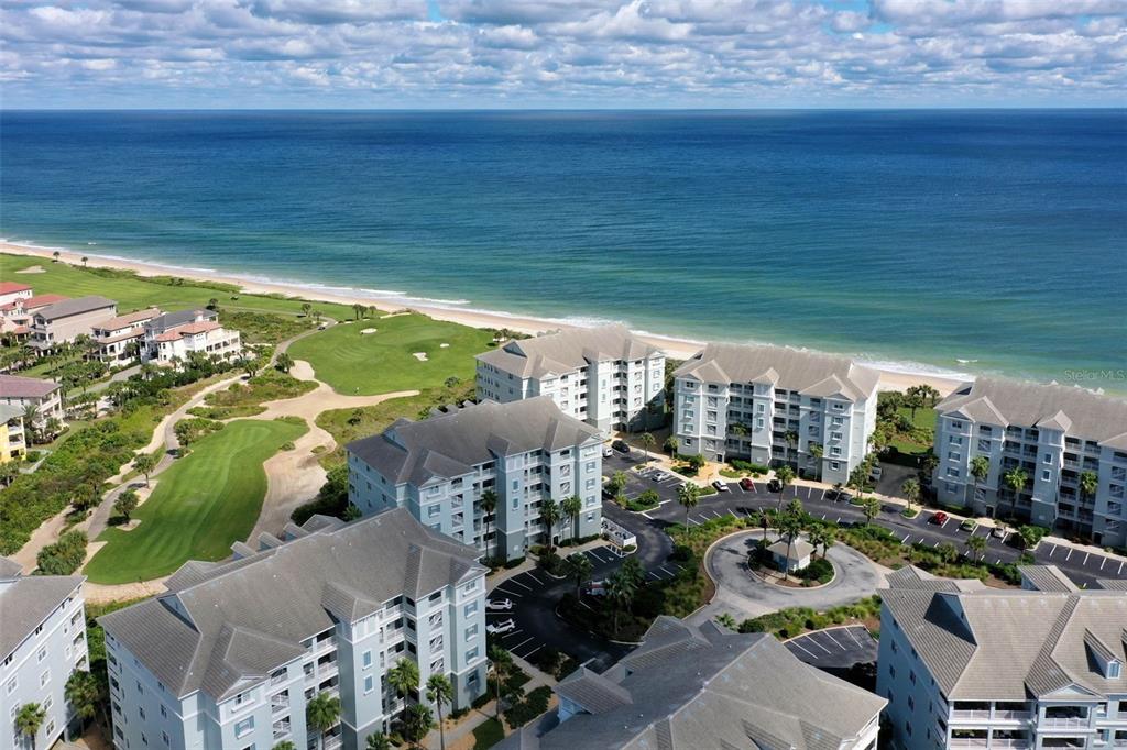 An aerial view shows multi-story apartment buildings situated next to a golf course and beach — 500 CINNAMON BEACH WAY UNIT 452, PALM COAST, FL