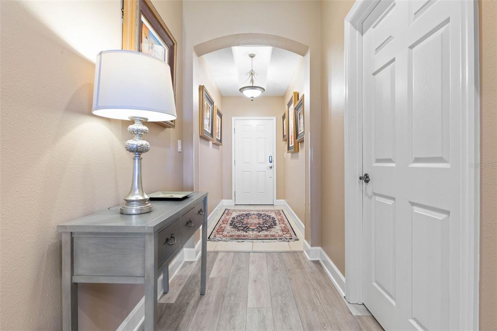 A hallway features light wood-look flooring, a console table with a lamp, and a white door — 500 CINNAMON BEACH WAY UNIT 452, PALM COAST, FL