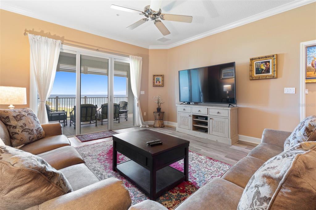 A living room with a large television, a coffee table, and a balcony overlooking the ocean — 500 CINNAMON BEACH WAY UNIT 452, PALM COAST, FL