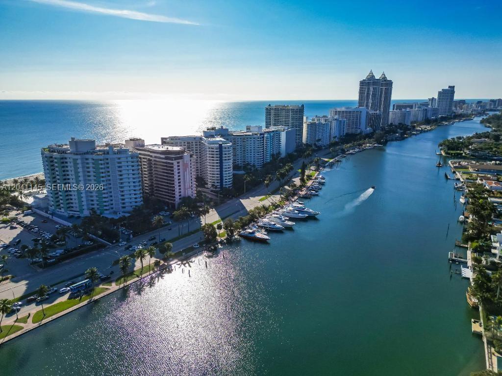An aerial view shows high-rise buildings along a coastline next to a canal with boats — 5225 Collins Ave # 914, Miami Beach FL 33140, MIAMI BEACH, FL