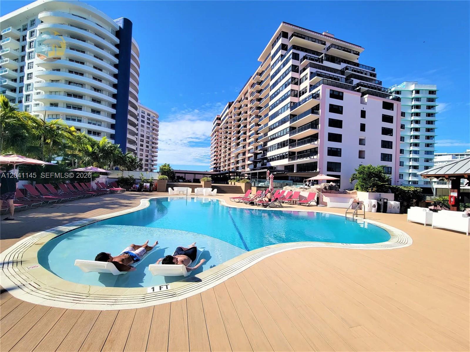 A swimming pool with lounge chairs sits on a deck between several large apartment buildings — 5225 Collins Ave # 914, Miami Beach FL 33140, MIAMI BEACH, FL