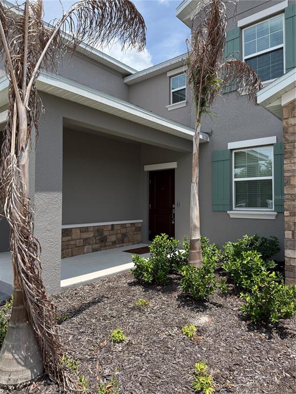 A gray two-story house exterior features a covered entryway, stone accents, and green shutters — 1885 FULFILLMENT DRIVE, KISSIMMEE, FL