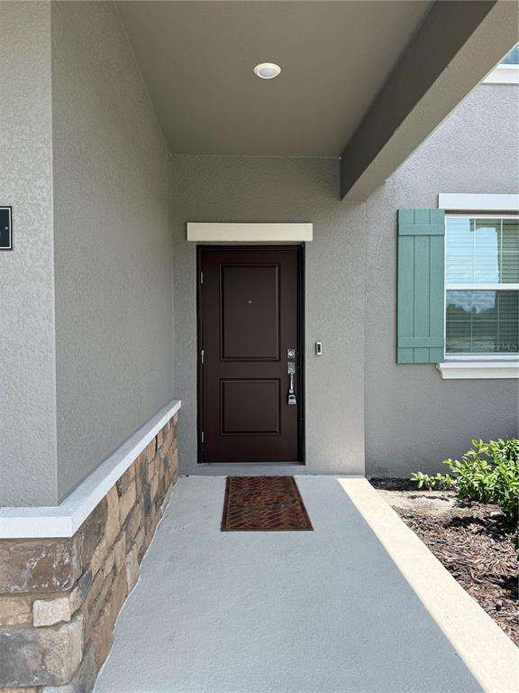 A covered entryway features a dark brown front door, stone siding, and a window with shutters — 1885 FULFILLMENT DRIVE, KISSIMMEE, FL