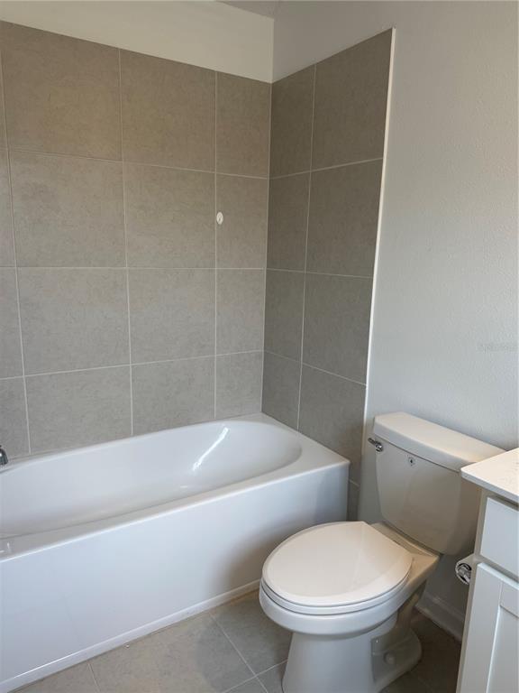 A bathroom features a white bathtub with gray tiled walls and a white toilet — 1885 FULFILLMENT DRIVE, KISSIMMEE, FL