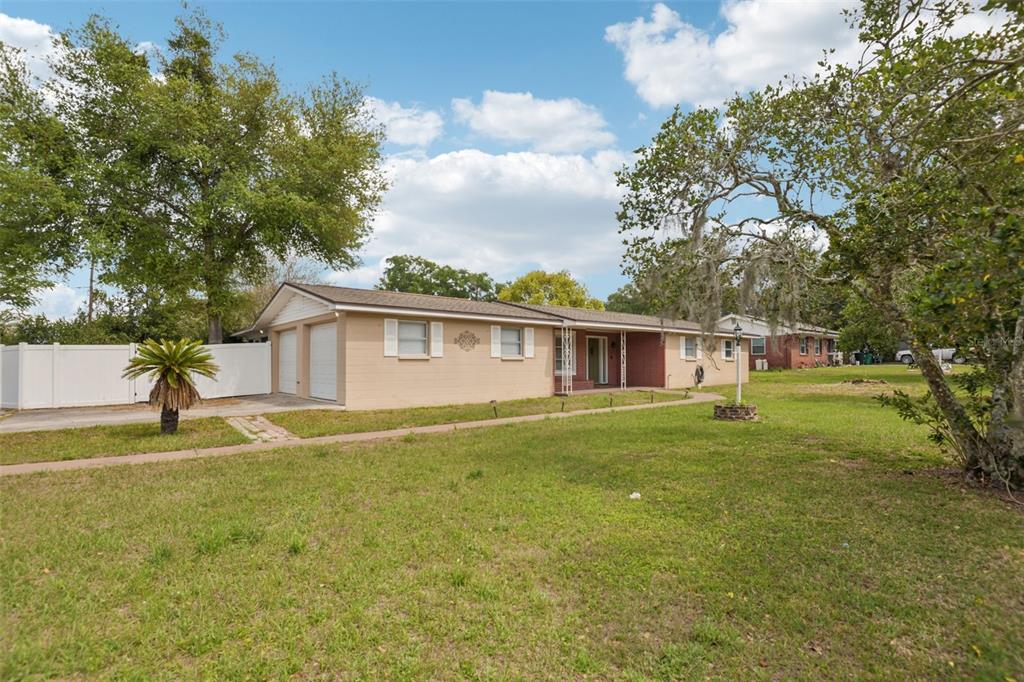 A single-story tan brick house with a two-car garage and a large front lawn — 5942 13TH STREET, ZEPHYRHILLS, FL