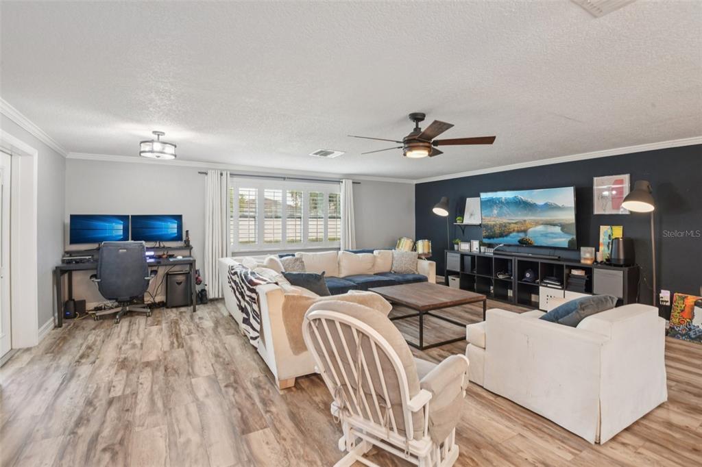A living room features a sectional sofa, a desk area, and a dark accent wall — 5942 13TH STREET, ZEPHYRHILLS, FL