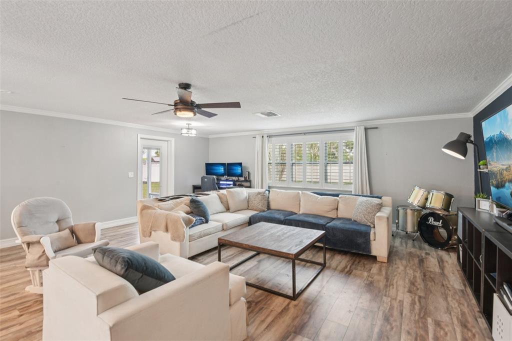 A living room features a large sectional sofa, a wooden coffee table, and drum set — 5942 13TH STREET, ZEPHYRHILLS, FL