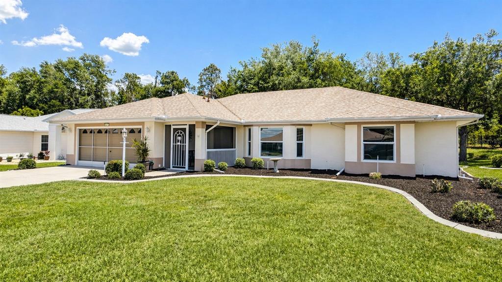 A single-story house with a tan exterior, a shingled roof, and a front lawn — 5277 INDIAN OCEAN LOOP, TAVARES, FL