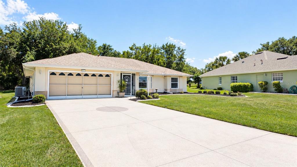 A single-story house with a beige exterior, a multi-car garage, and a concrete driveway — 5277 INDIAN OCEAN LOOP, TAVARES, FL