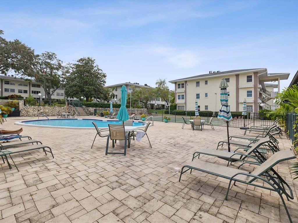 A living room with light wood floors, a blue recliner, and an open kitchen area — 1235 S HIGHLAND AVENUE UNIT 2-207, CLEARWATER, FL