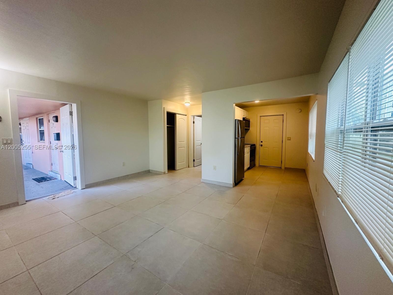 An open-concept living area features light tile flooring, white walls, and an adjacent kitchen — 1708 Van Buren St # 6, Hollywood FL 33020, HOLLYWOOD, FL