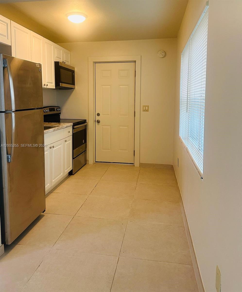 This kitchen features stainless steel appliances, white cabinets, and light-colored tile flooring — 1708 Van Buren St # 6, Hollywood FL 33020, HOLLYWOOD, FL