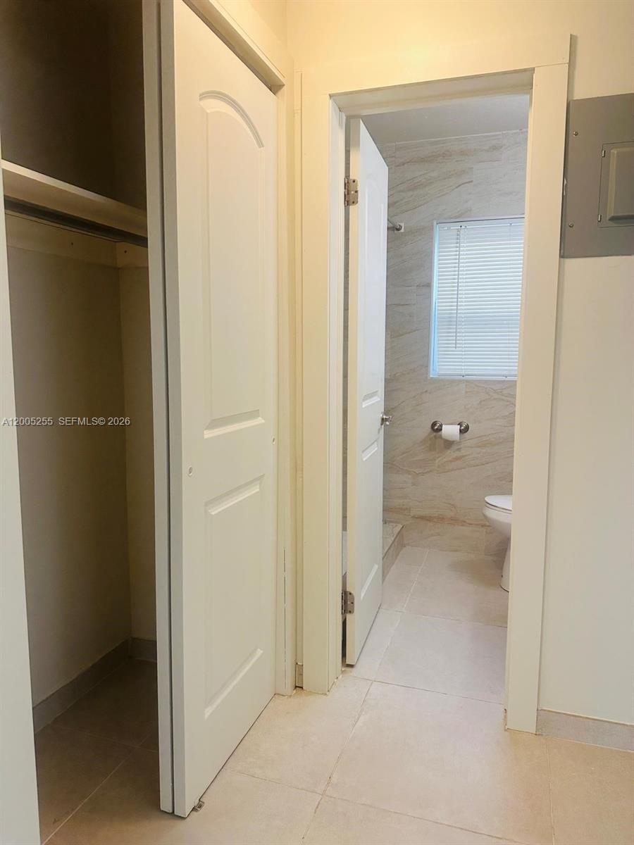 A closet door stands open next to a doorway leading into a tiled bathroom — 1708 Van Buren St # 6, Hollywood FL 33020, HOLLYWOOD, FL