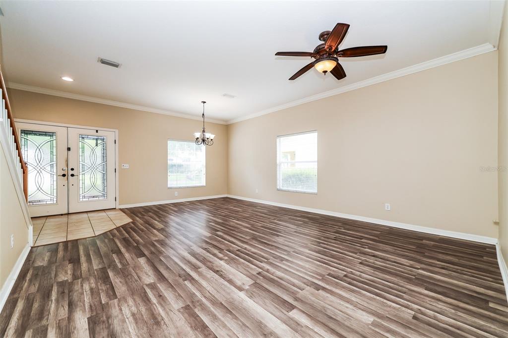 An empty living room features wood-look flooring, a ceiling fan, and a front entryway — 14831 HERONGLEN DRIVE, LITHIA, FL