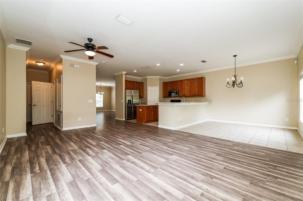An open-concept living area features wood-look flooring, a kitchen with wood cabinets, and tile flooring — 14831 HERONGLEN DRIVE, LITHIA, FL