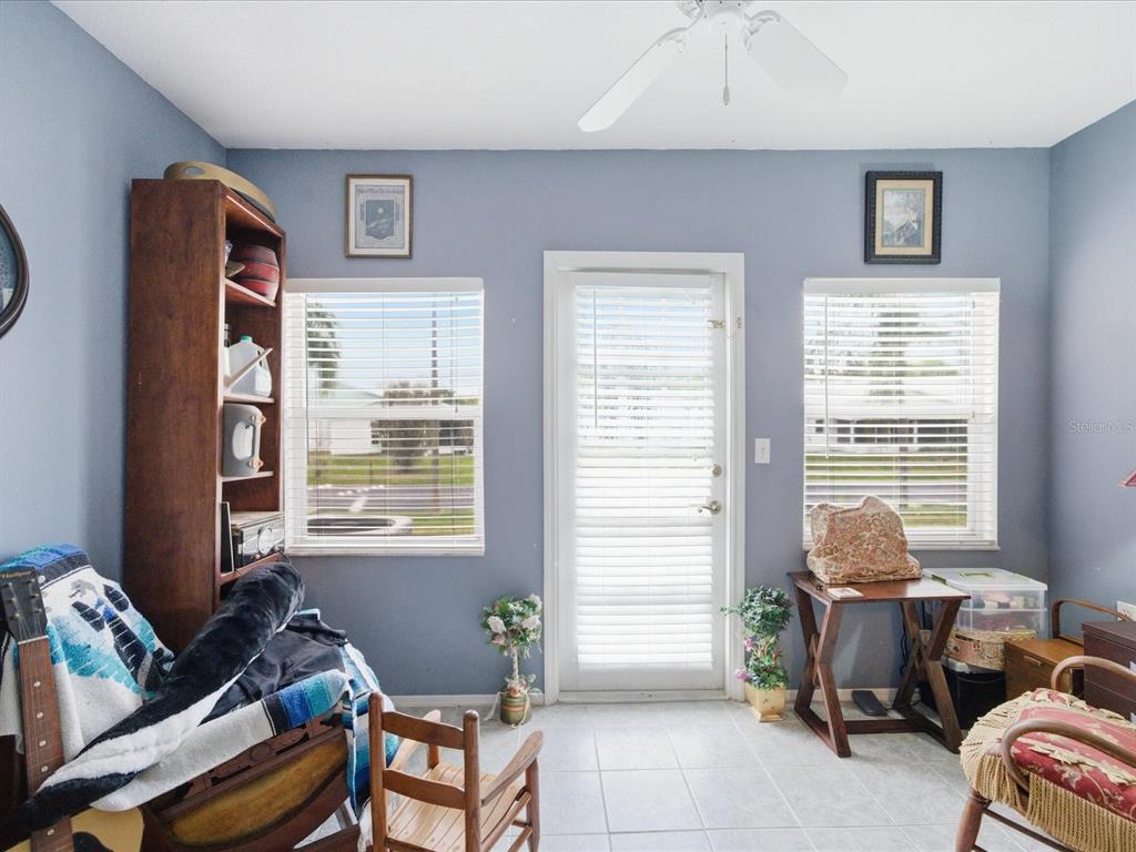 A room with blue walls, tile flooring, a ceiling fan, two windows, and a door — 4209 AVANTI CIRCLE, NEW PORT RICHEY, FL