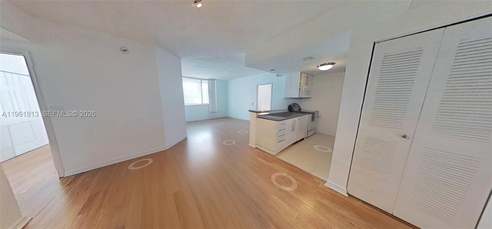 An open-concept living area features wood-style flooring, a kitchen with white cabinetry, and a closet — 275 NE 18th St # 1705, Miami FL 33132, MIAMI, FL