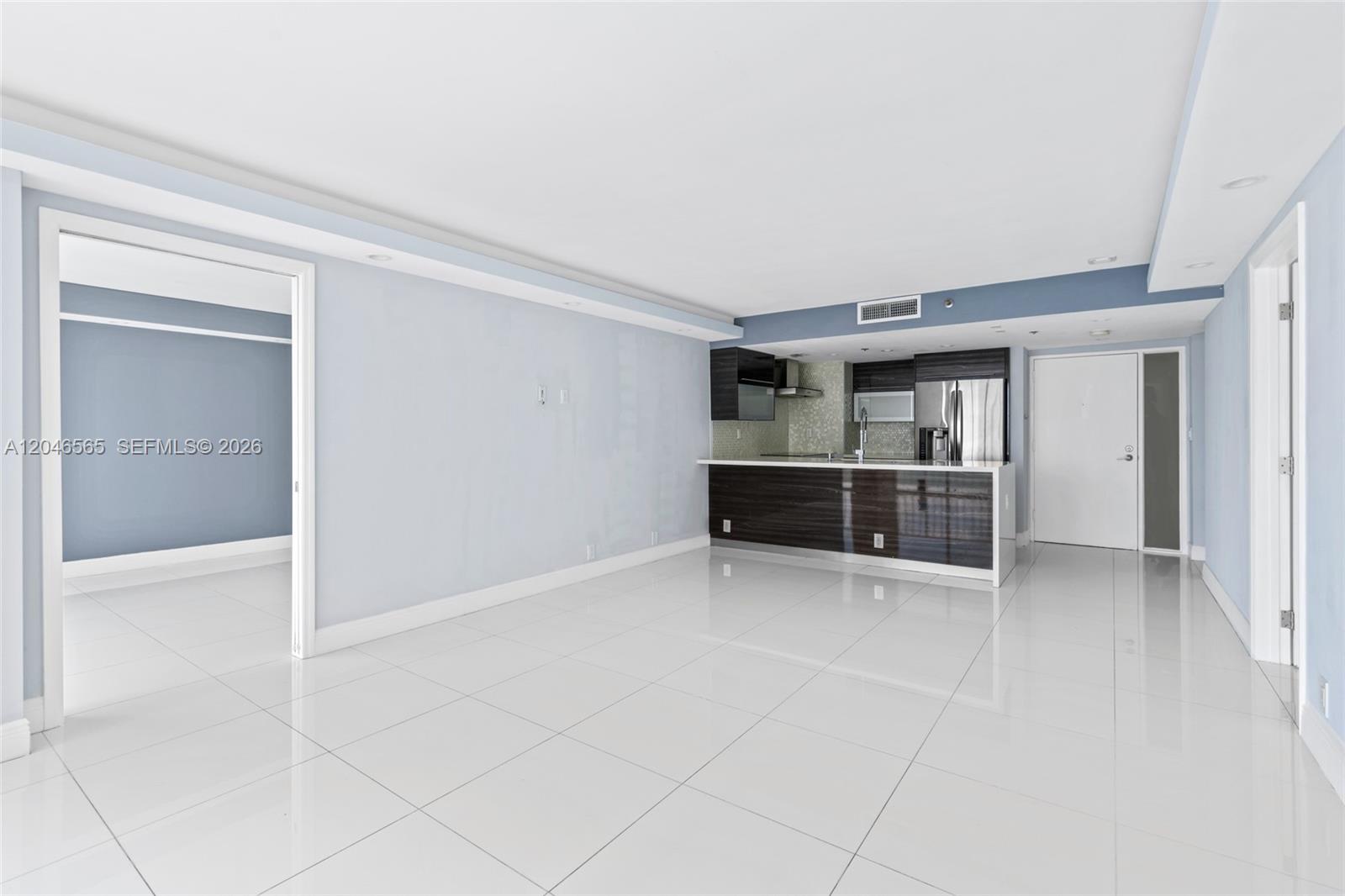 An open-concept living area features white tile flooring, light blue walls, and a modern kitchen — NORTH BAY VILLAGE, FL