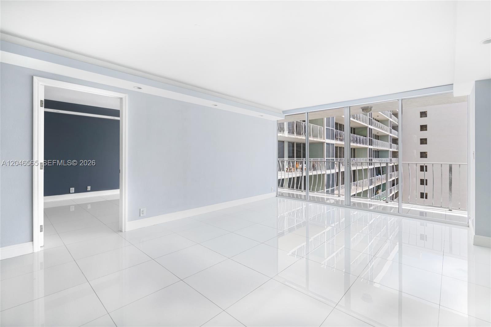 A bright room with white tile floors, light blue walls, and floor-to-ceiling windows — NORTH BAY VILLAGE, FL