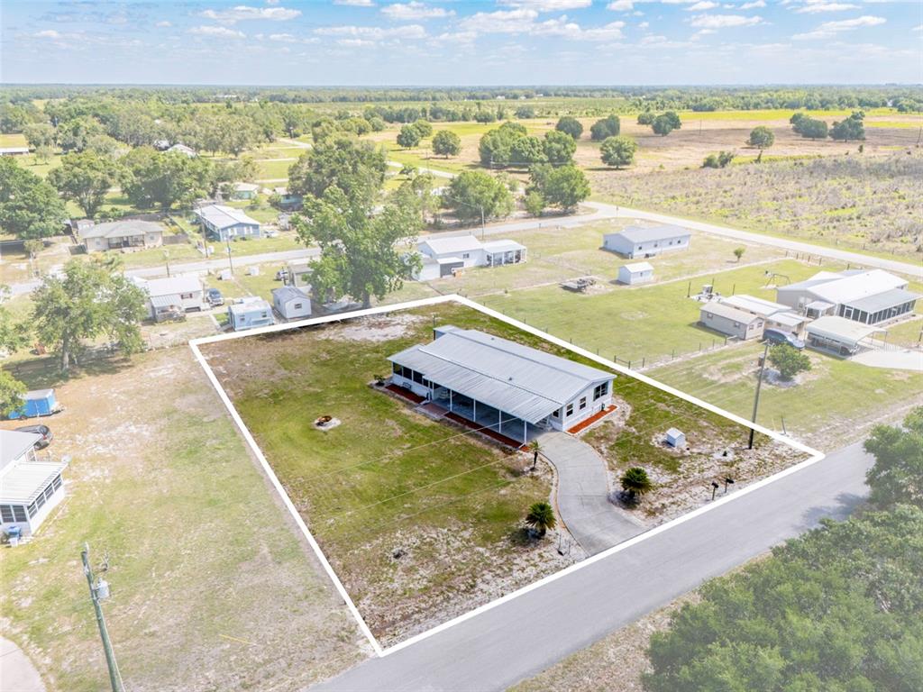 An aerial view shows a single-story house with a large porch on a grassy lot — 1586 NE GRAPEFRUIT STREET, ARCADIA, FL