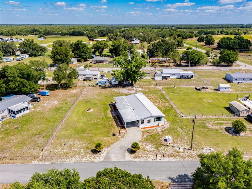 An aerial view shows a single-story house with a metal roof and a concrete driveway — 1586 NE GRAPEFRUIT STREET, ARCADIA, FL