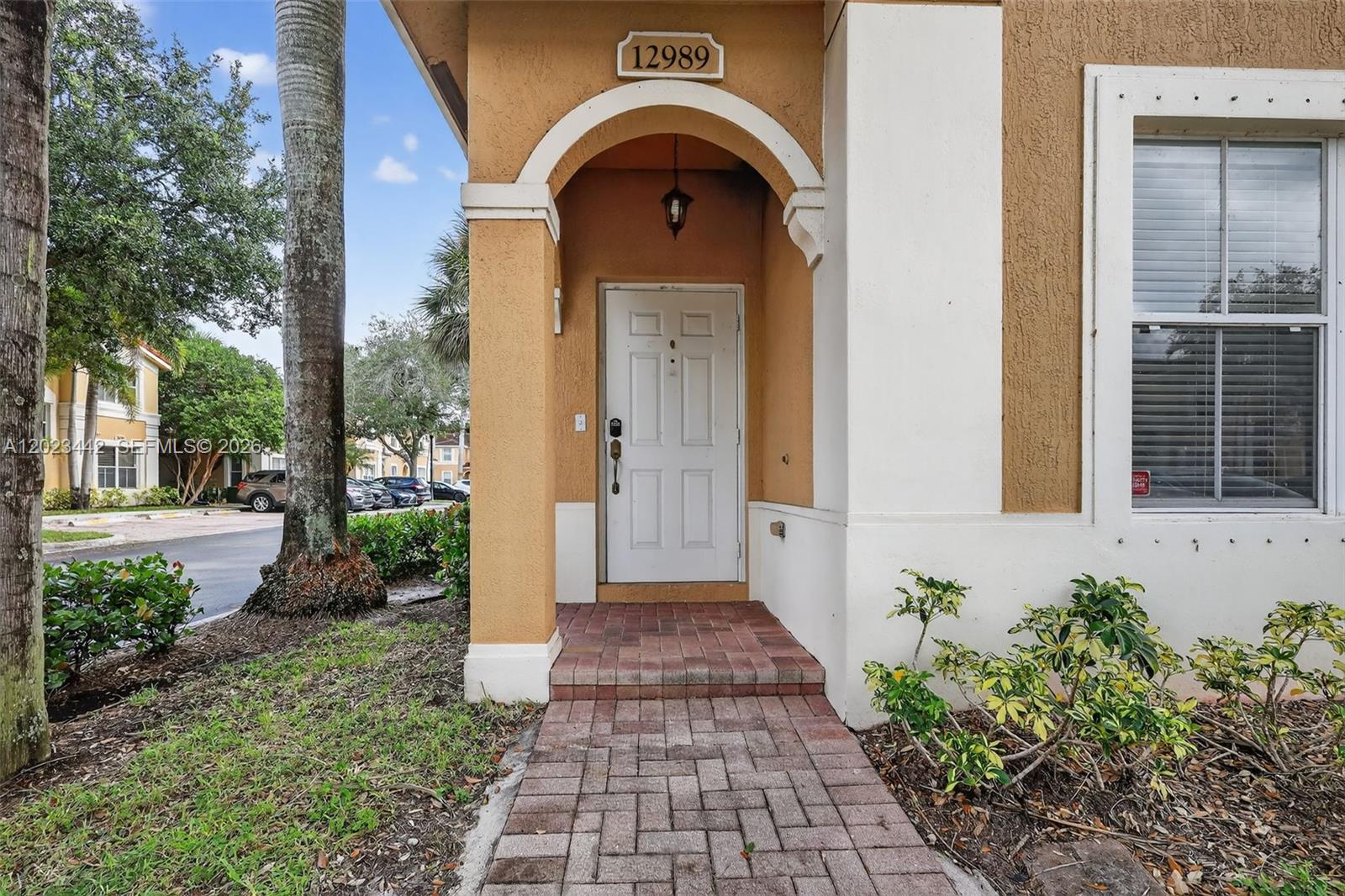 The exterior entrance features a white door, a brick walkway, and a tan stucco facade — 12989 SW 30th Ct # 135, Miramar FL 33027, MIRAMAR, FL