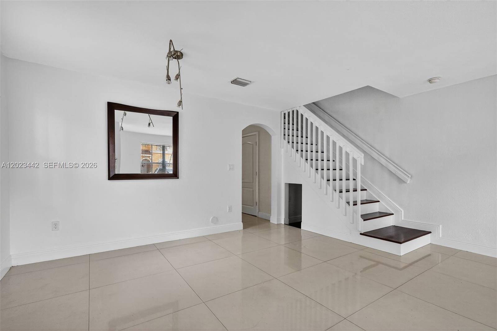 An empty room features white walls, large floor tiles, and a staircase with dark treads — 12989 SW 30th Ct # 135, Miramar FL 33027, MIRAMAR, FL