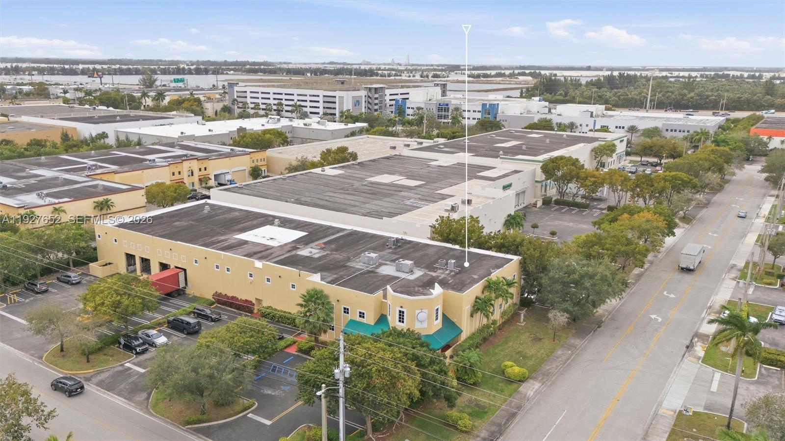 An aerial view shows a yellow commercial warehouse building with a flat roof and parking — 3850 NW 114th Ave, Doral FL 33178, DORAL, FL