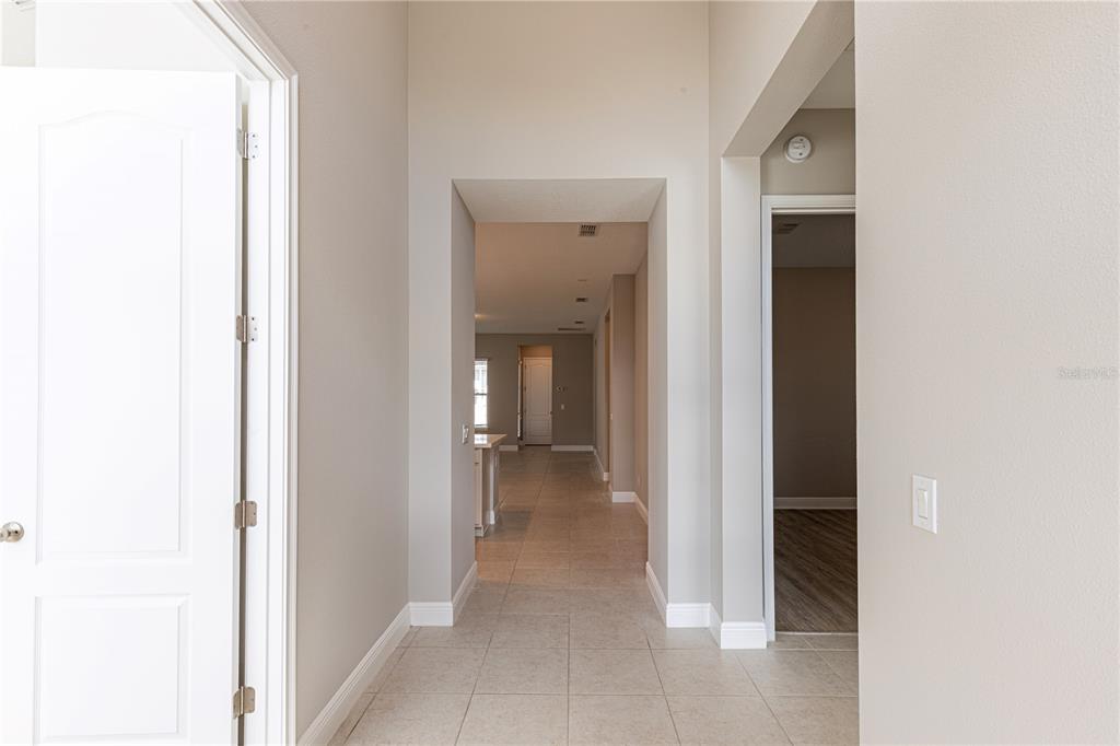 A tiled entryway leads to a hallway with a view of an open kitchen area — 9233 SMITHIES STREET, ORLANDO, FL
