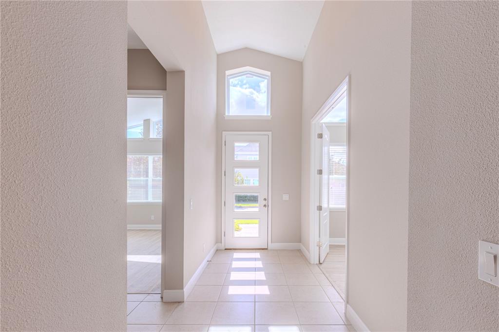 A bright entryway features light tile flooring, a white front door, and a vaulted ceiling — 9233 SMITHIES STREET, ORLANDO, FL