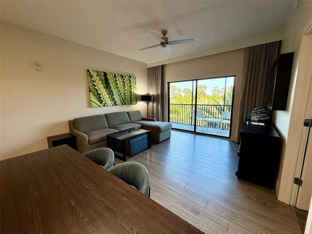 A living room features a sectional sofa, dining table, and sliding glass doors to a balcony — 14501 GROVE RESORT AVE UNIT 2413, WINTER GARDEN, FL