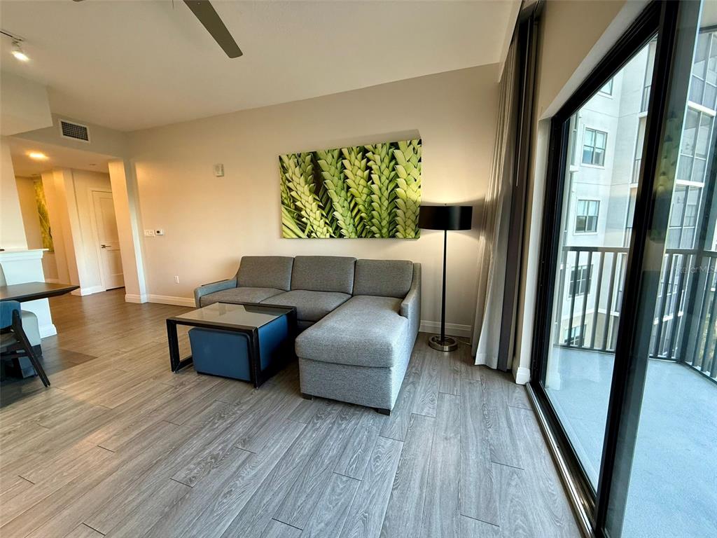 A living room features a gray sectional sofa, a coffee table, and a balcony view — 14501 GROVE RESORT AVE UNIT 2413, WINTER GARDEN, FL