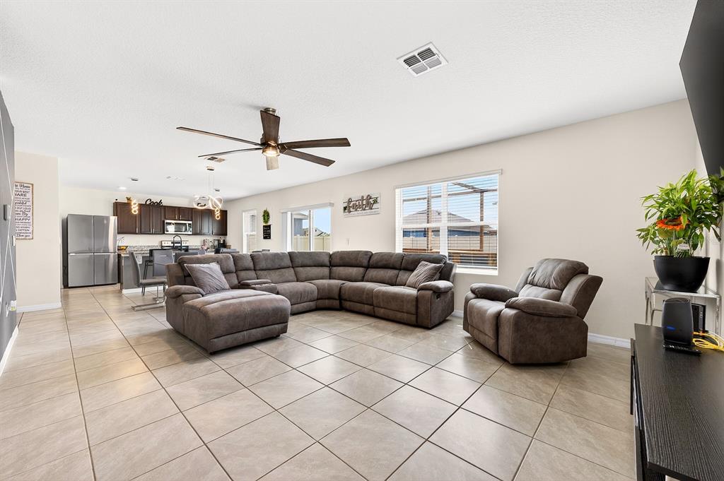 A living room with tile flooring, a large sectional sofa, and an open-concept kitchen — 3353 EASTGROVE TERRACE, SANFORD, FL