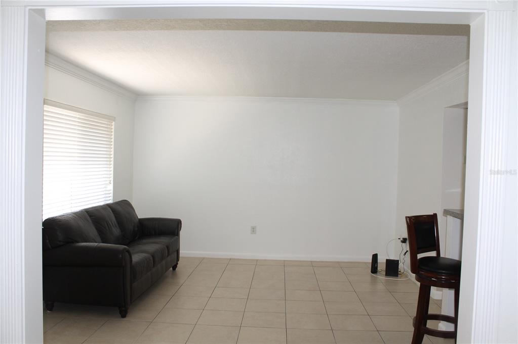 A living room with a dark leather sofa, tile flooring, and white walls — 151 OYSTER BAY CIRCLE UNIT 200, ALTAMONTE SPRINGS, FL