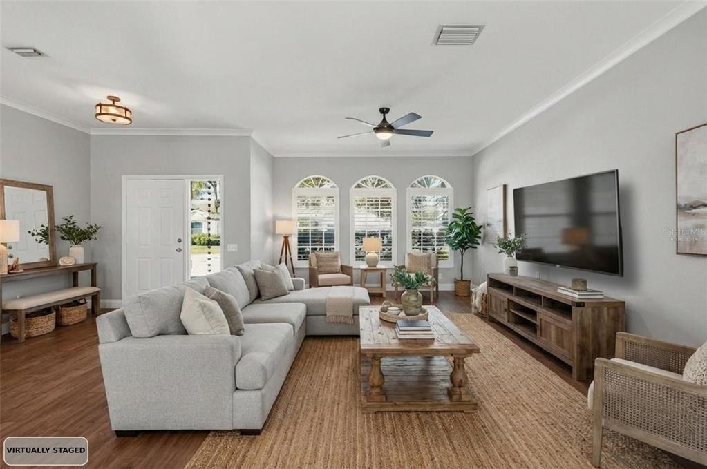 A living room features a grey sectional sofa, wooden coffee table, and a wall-mounted television — 1857 RIVEREDGE DRIVE, TARPON SPRINGS, FL
