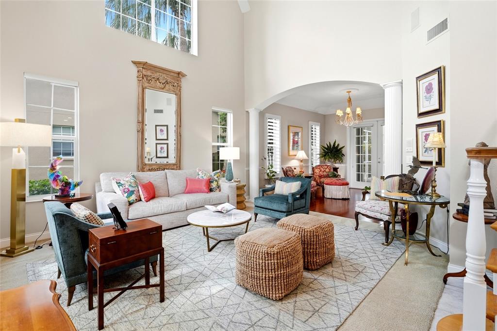 A bright living room features a high ceiling, a large mirror, and patterned area rugs — 1246 DARLINGTON OAK CIRCLE NE, ST PETERSBURG, FL