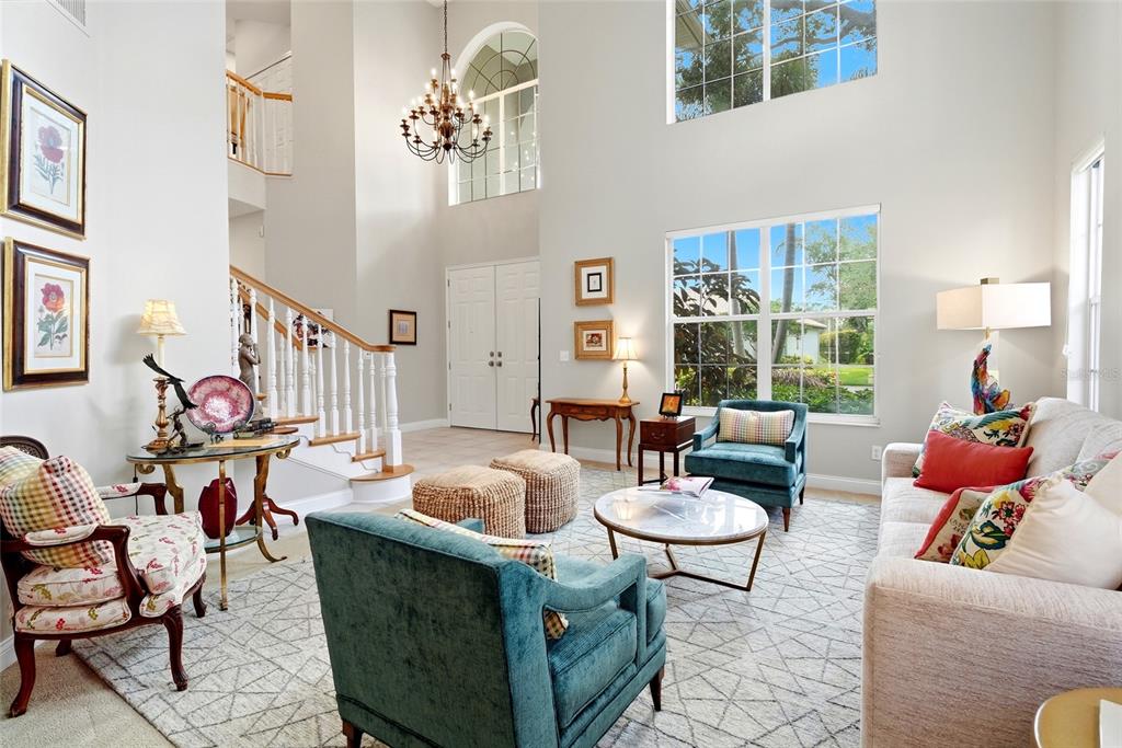 A bright living room features a high ceiling, a staircase, and multiple seating areas — 1246 DARLINGTON OAK CIRCLE NE, ST PETERSBURG, FL