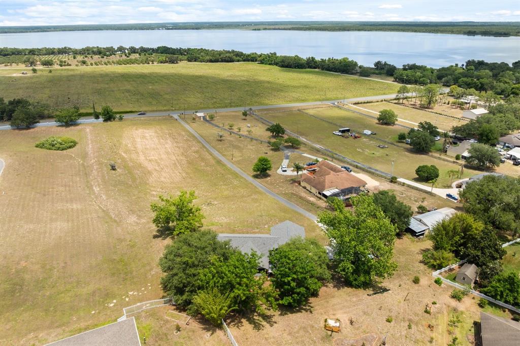An aerial view shows two houses on a large, grassy lot near a lake — 37153 COUNTY ROAD 452, GRAND ISLAND, FL