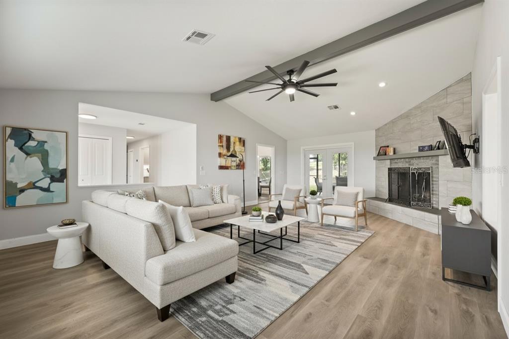 A living room features a vaulted ceiling, a stone fireplace, and light wood-look flooring — 37153 COUNTY ROAD 452, GRAND ISLAND, FL