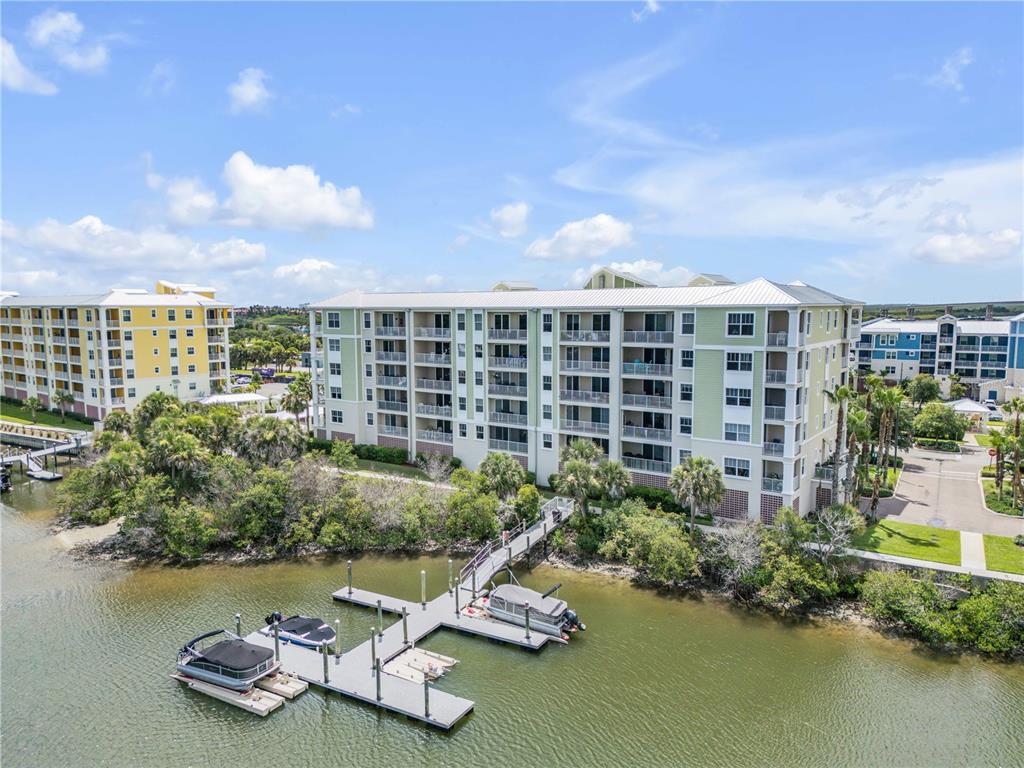 An aerial view of a multi-story apartment building with a private dock and boats — 5 RIVERWALK DRIVE UNIT 506, NEW SMYRNA BEACH, FL