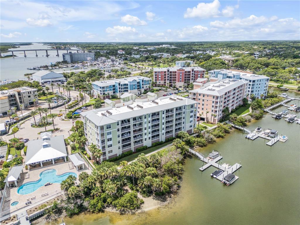 An aerial view shows a multi-story apartment complex with a pool and boat docks — 5 RIVERWALK DRIVE UNIT 506, NEW SMYRNA BEACH, FL