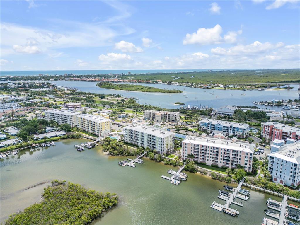 An aerial view of waterfront apartment buildings and boat docks along a coastal bay — 5 RIVERWALK DRIVE UNIT 506, NEW SMYRNA BEACH, FL