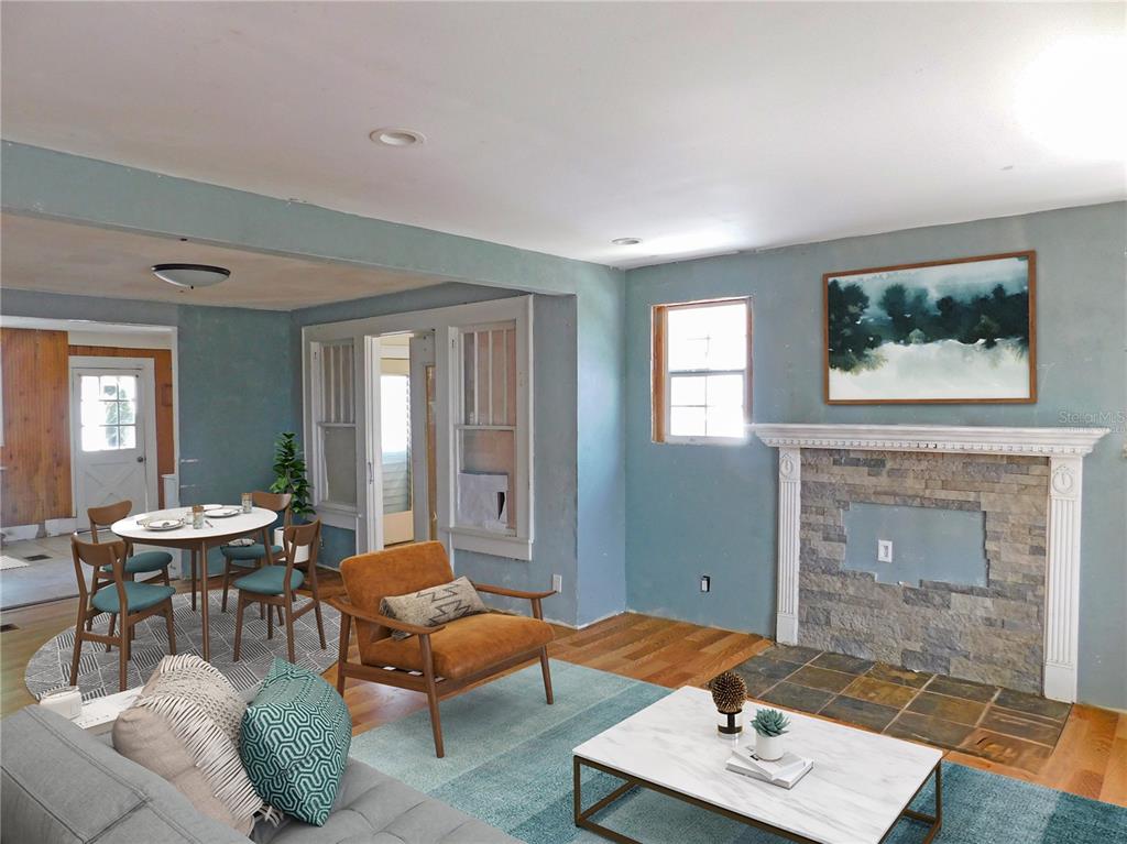 A living room with blue walls, a stone fireplace, hardwood floors, and an adjacent dining area — 6400 12TH STREET, ZEPHYRHILLS, FL
